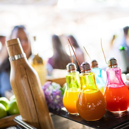Intercontinental Budapest By Ihg Exterior foto The photo displays a vibrant array of colorful beverages in bulb-shaped glass bottles. There are several drinks in various shades, including yellow, orange, pink, and blue, each topped with a straw. In the foreground, a bamboo bottle is also visible,