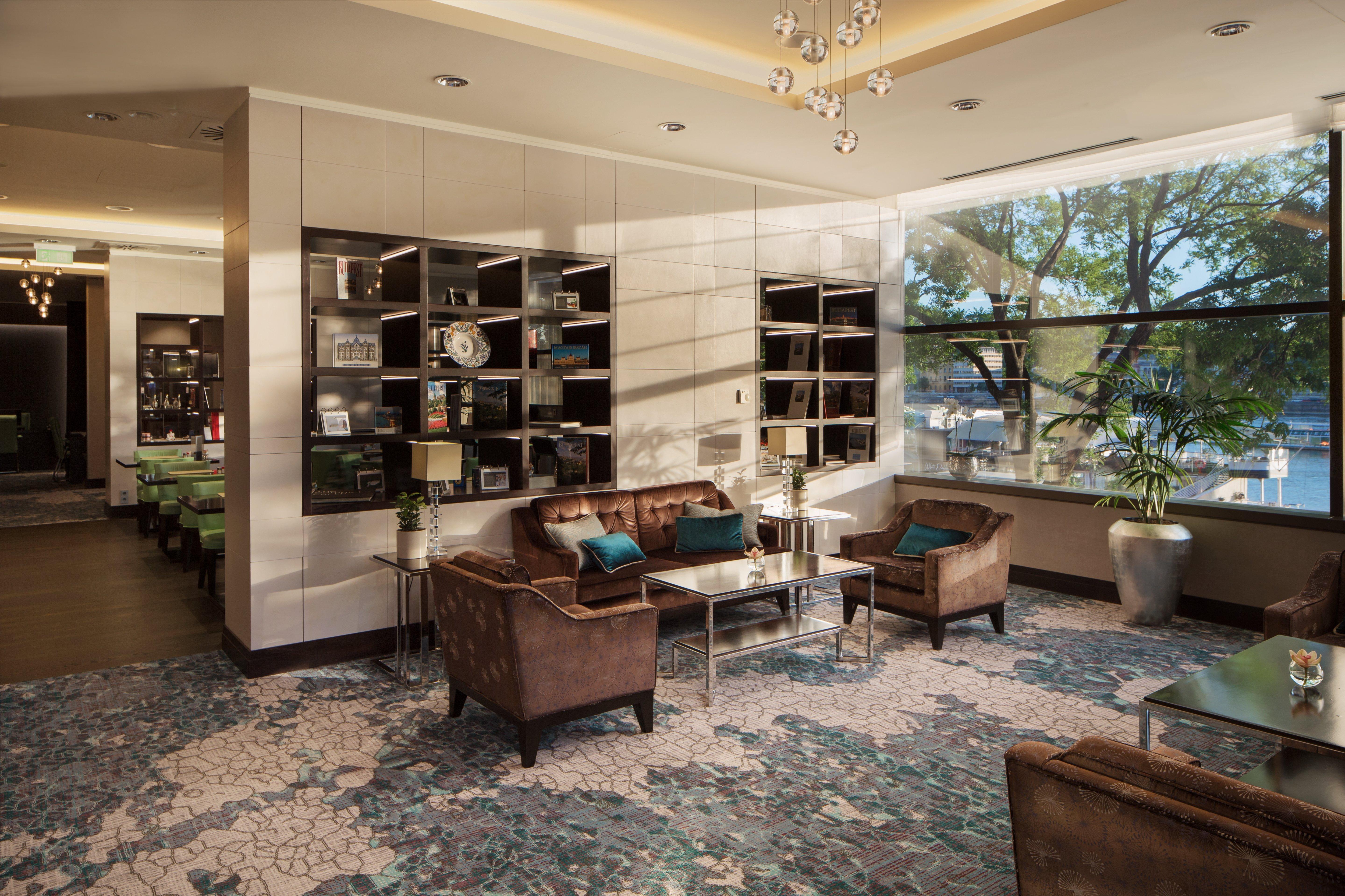 Intercontinental Budapest By Ihg Exterior foto The photo depicts a modern lounge area featuring comfortable brown leather seating, including two armchairs and a sofa, arranged around a glass coffee table. A decorative shelf unit against the wall displays various items, adding a touch of elegance 