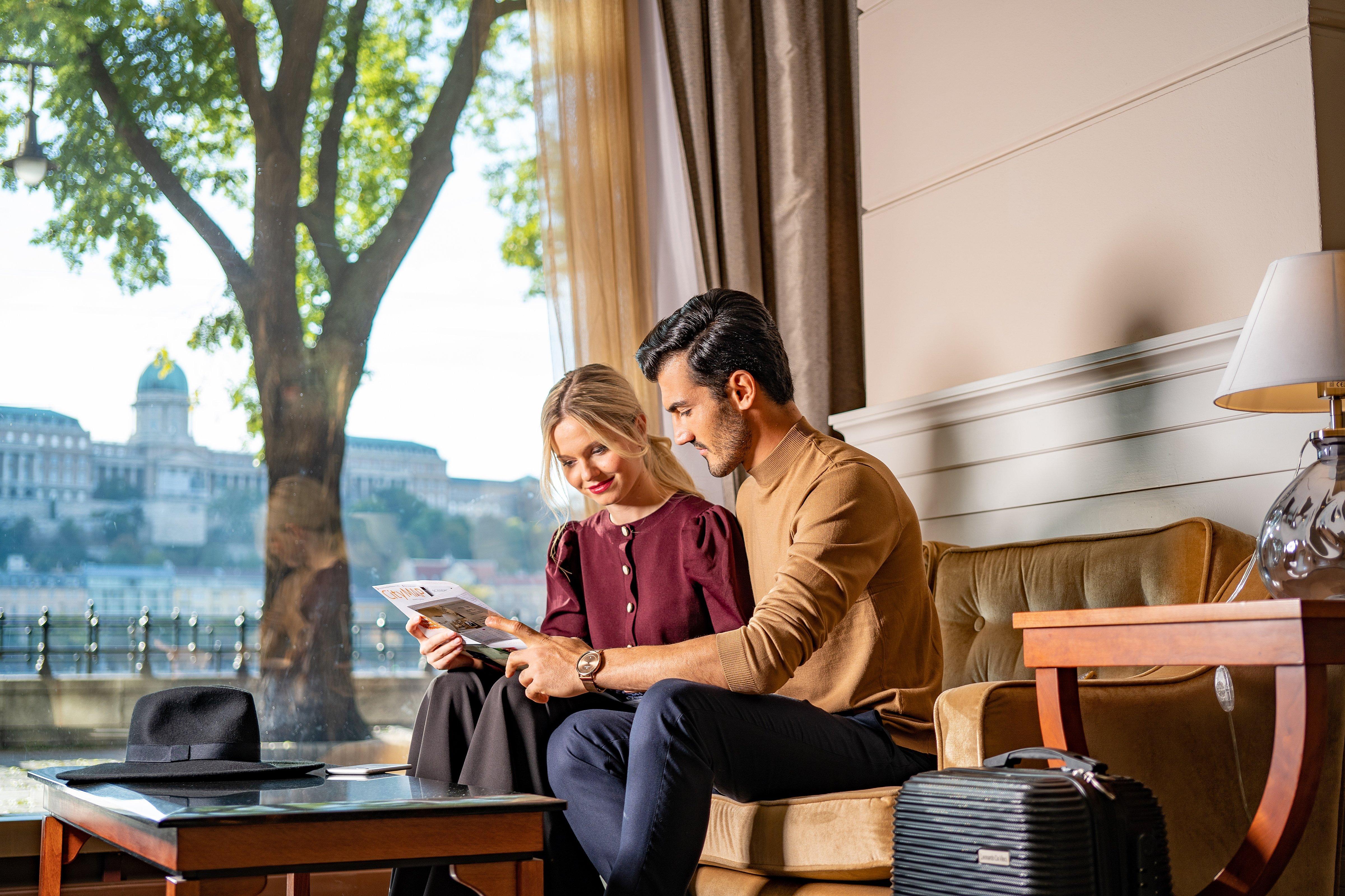 Intercontinental Budapest By Ihg Exterior foto The photo shows a couple sitting together on a couch in a well-lit room. They are looking at something on a piece of paper or a document. The man, dressed in a tan sweater, is focused intently on the paper, while the woman beside him, wearing a dark 