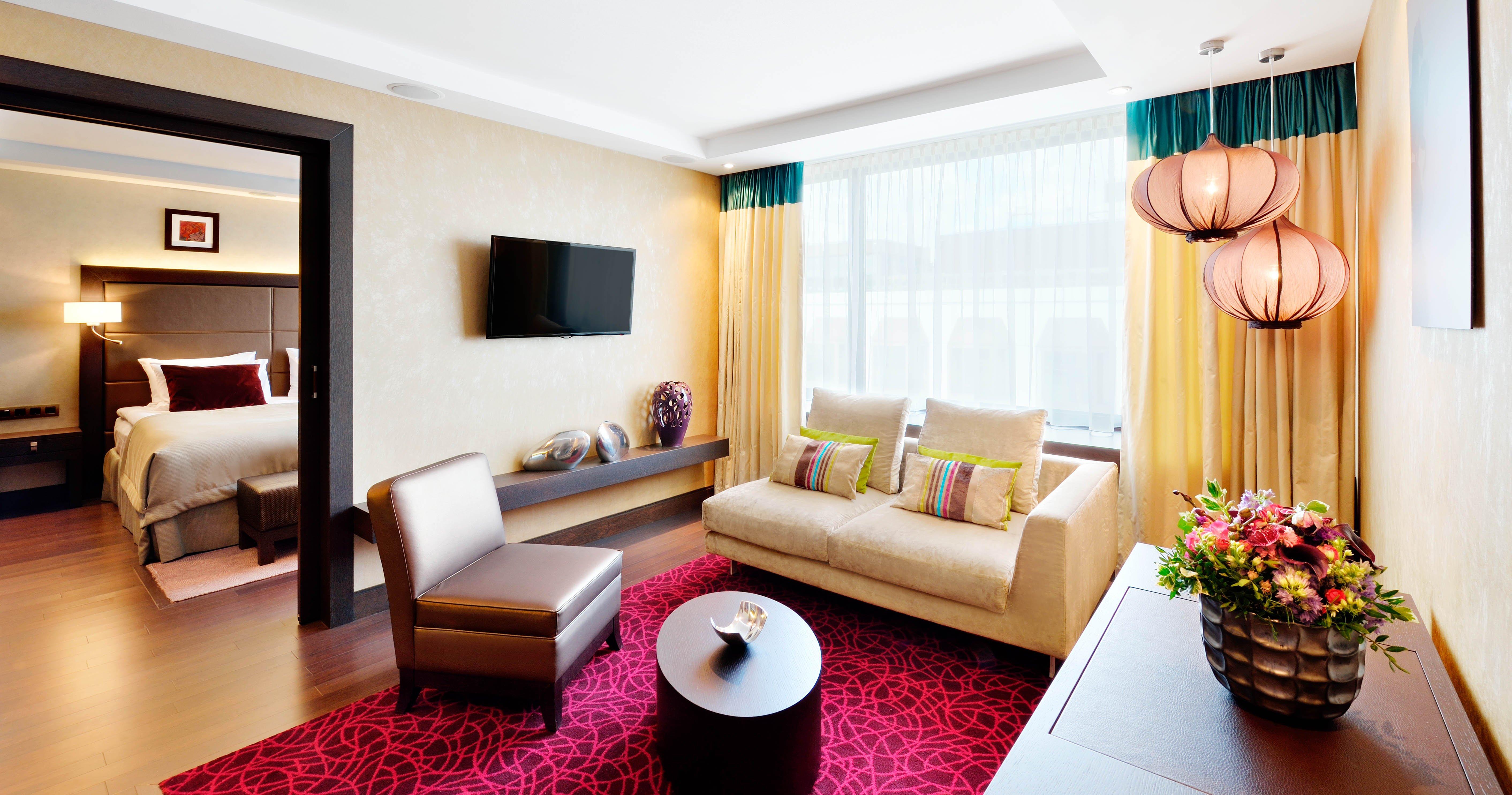 Intercontinental Budapest By Ihg Exterior foto The photo shows a modern living area with a comfortable atmosphere. There is a light-colored sofa adorned with colorful throw pillows, paired with a dark, stylish chair. A round coffee table is positioned in the center, and a decorative item sits on 