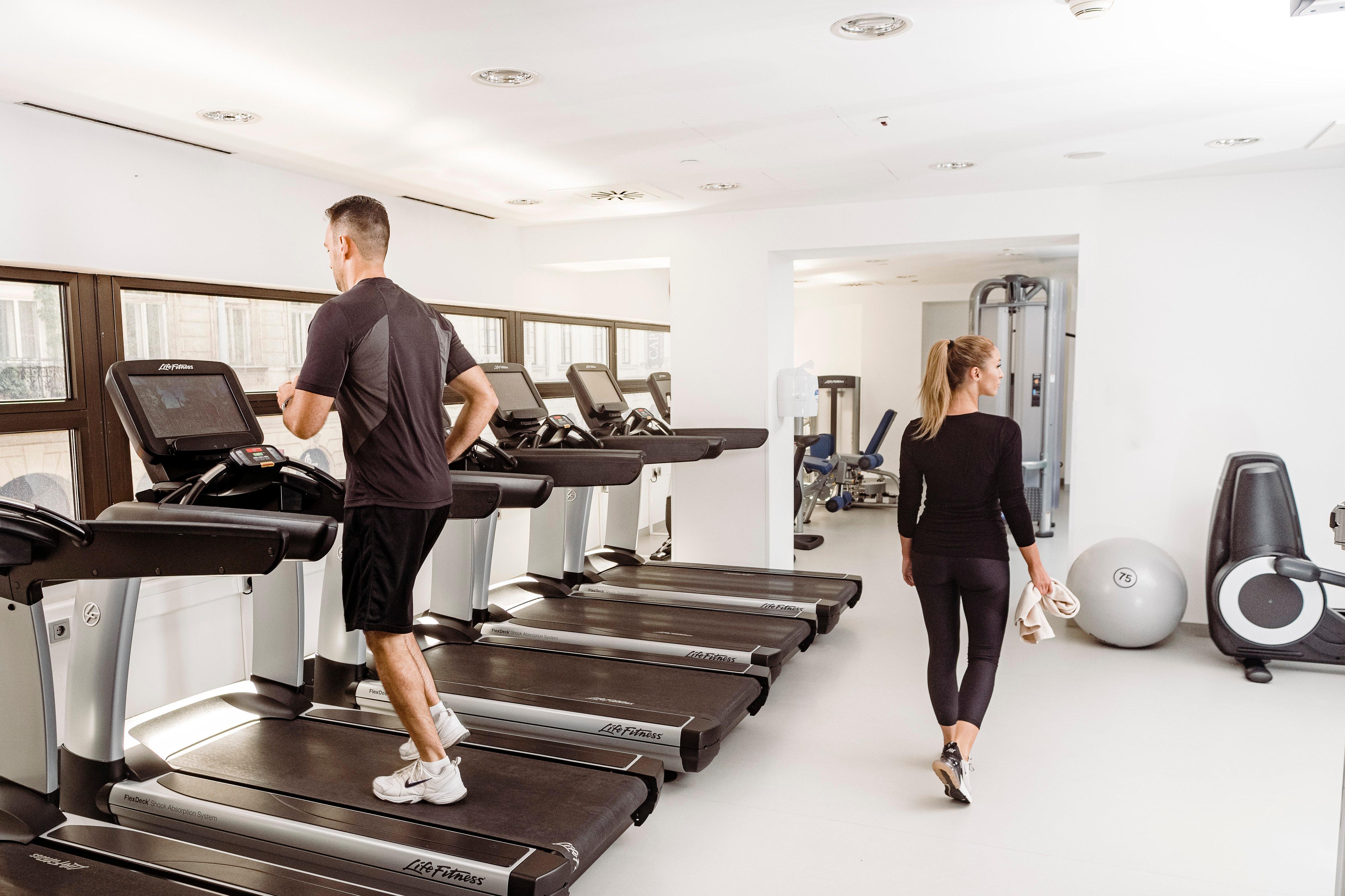 Intercontinental Budapest By Ihg Exterior foto The photo shows a bright, modern gym. In the foreground, a man is running on a treadmill. He is dressed in athletic wear, consisting of a short-sleeve shirt and shorts. In the background, a woman is walking past him, also in athletic clothing. The gy