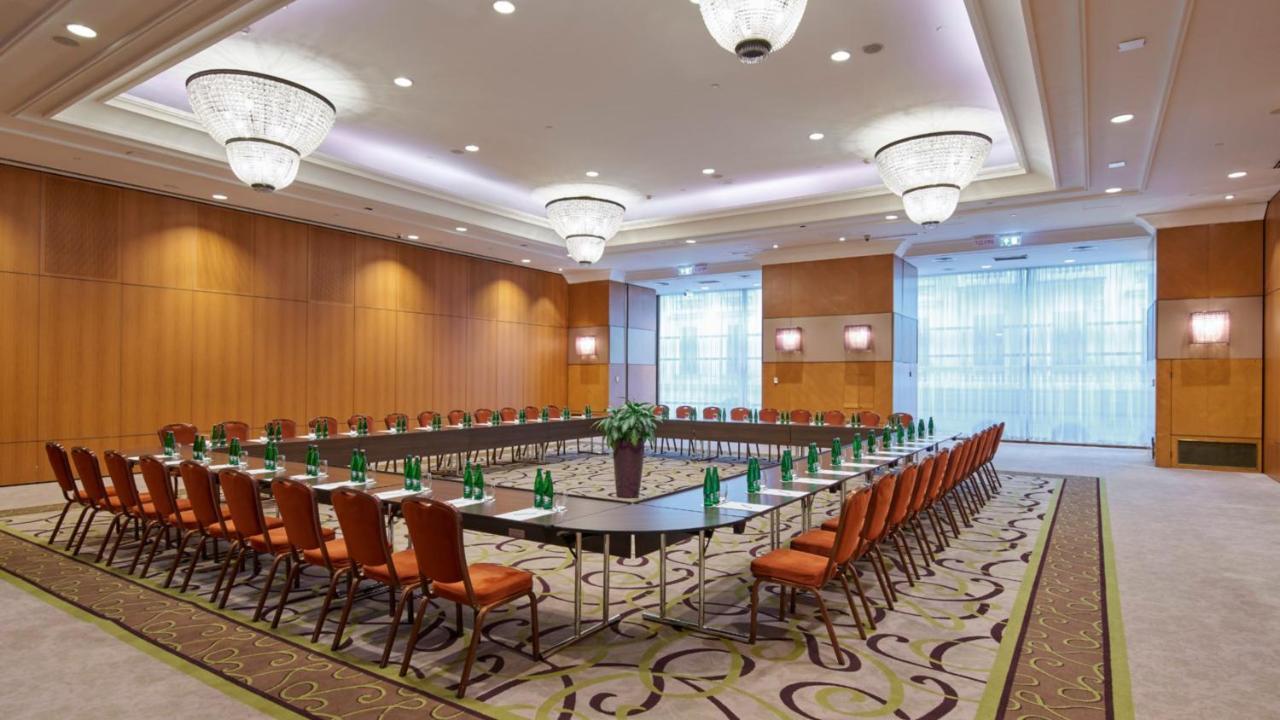 Intercontinental Budapest By Ihg Exterior foto The photo shows a well-organized conference room set up for a meeting or seminar. It features a large rectangular table at the center, surrounded by numerous chairs arranged in a circular or U-shape configuration. The chairs are upholstered in a warm