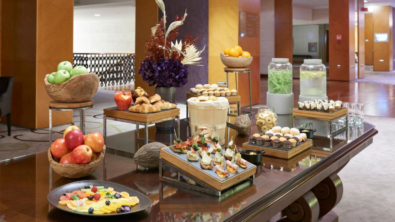 Intercontinental Budapest By Ihg Exterior foto The photo showcases an elegant display of a variety of foods, likely set up in a buffet or catering arrangement. There are multiple wooden trays and platters featuring an assortment of items:

1. **Fruits**: There are green and red apples, along with